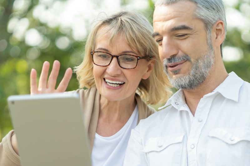 Aged senior couple waving hands greeting Joshua Tree Optimized Homeowner on a virtual tree consultation call