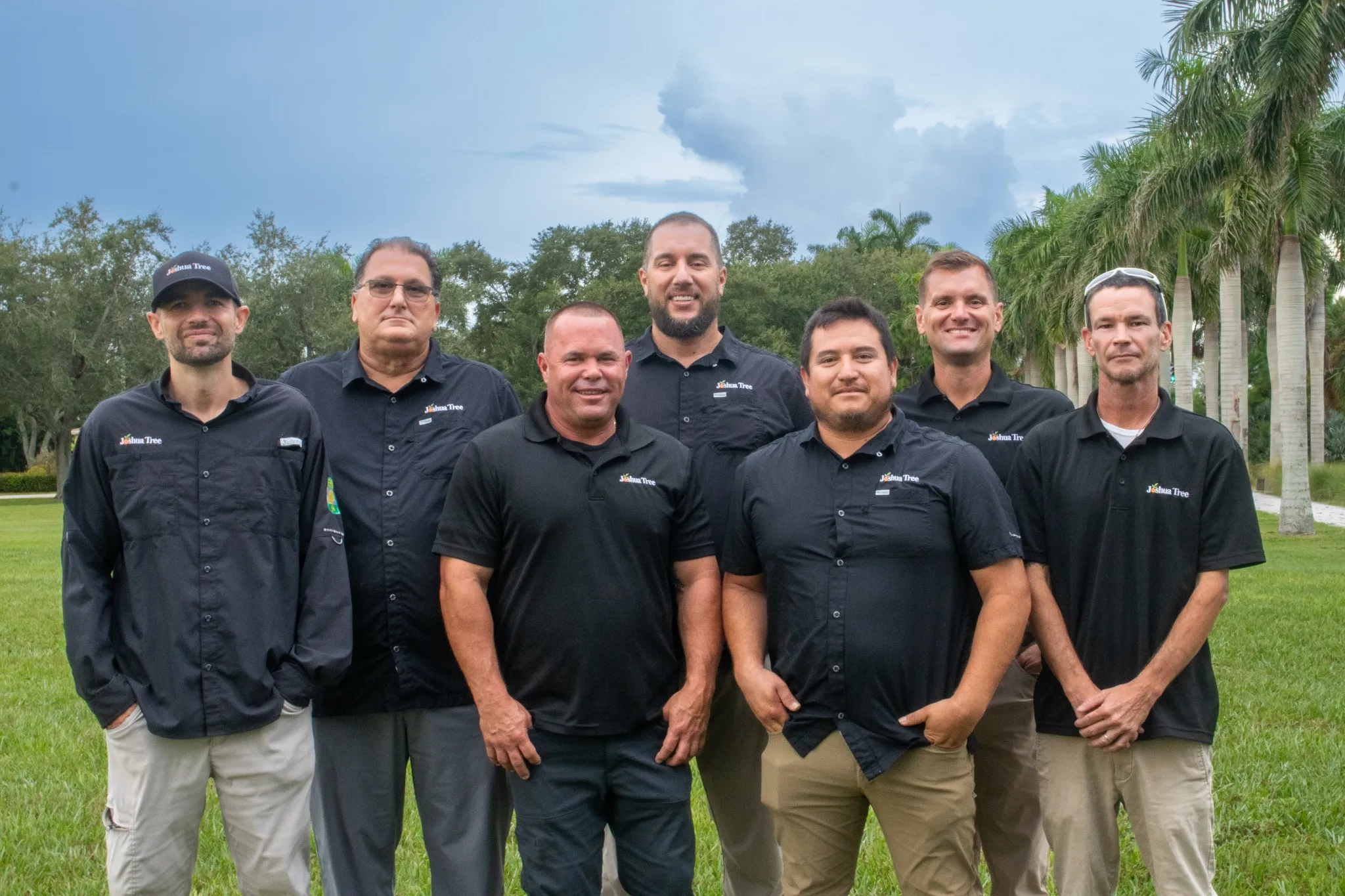 Joshua Tree Inc. tree care team standing together in Fort Myers, Florida with palm trees in the background